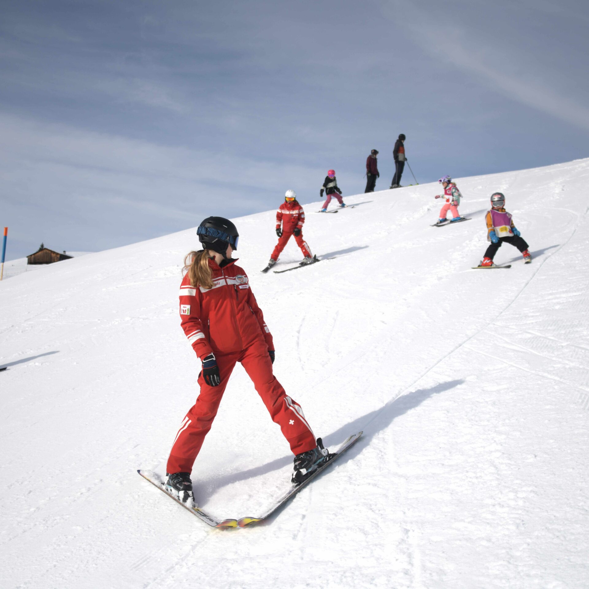 Zwei Skilehrerinnen fahren mit kleinen Kindern im Stemmbogen die Piste runter