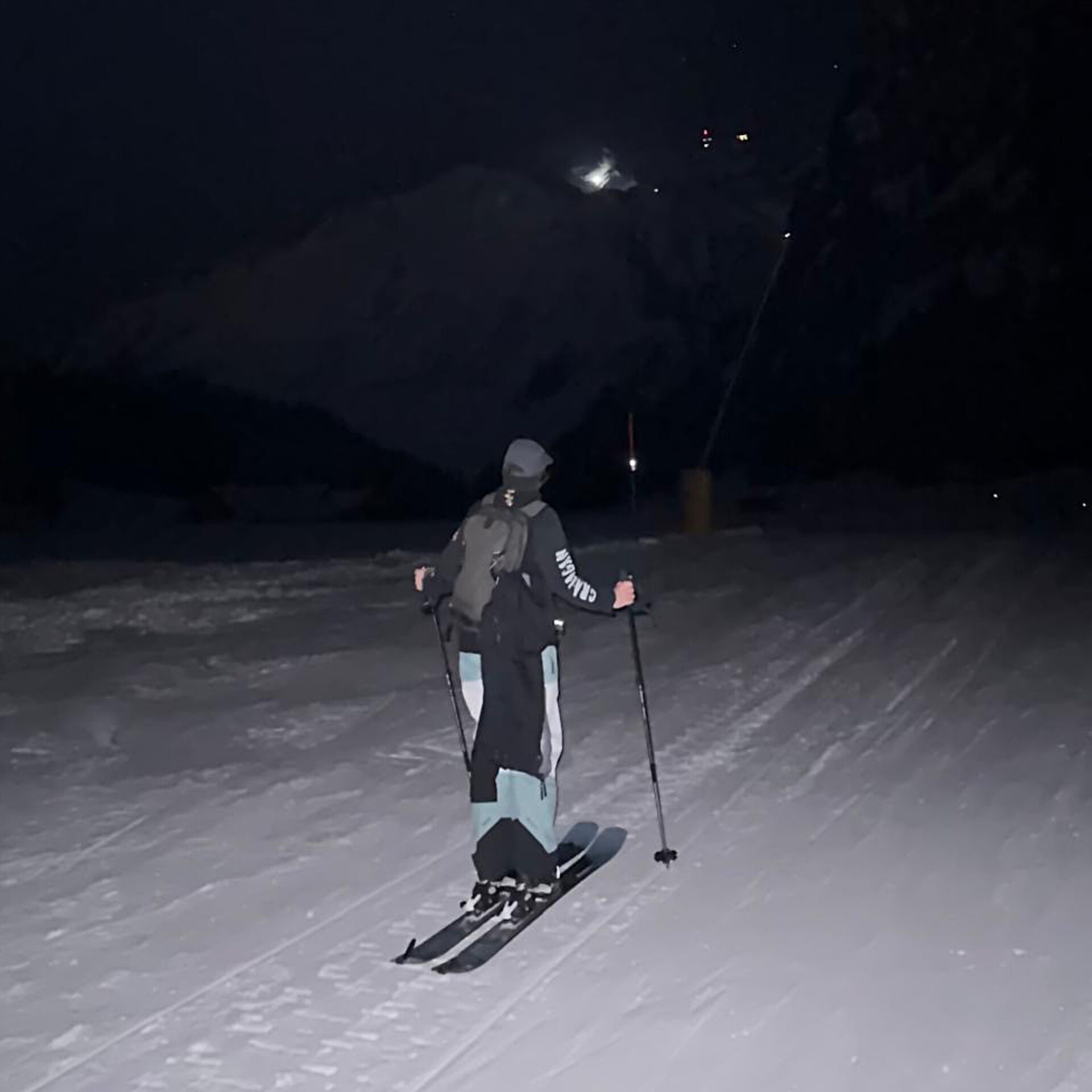 Person läuft auf Skitouren Ski bei Nacht über eine Piste