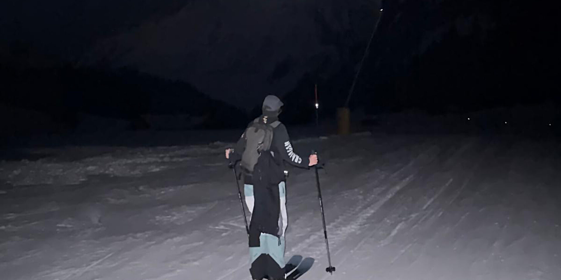 Person läuft auf Skitouren Ski bei Nacht über eine Piste